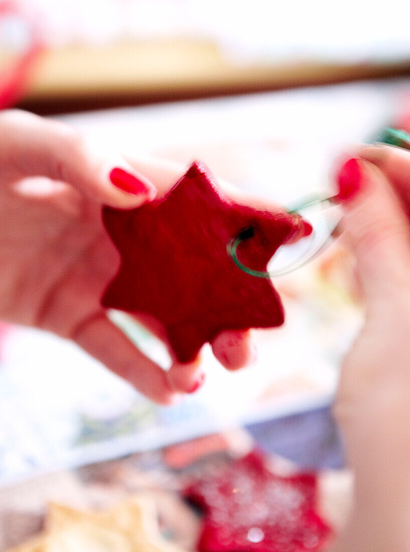 Woman threading red star-shaped Christmas decorations
