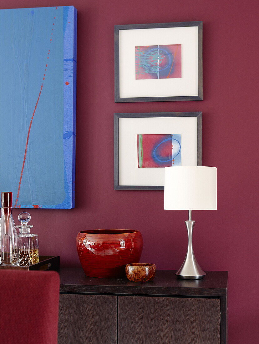 Modern art and homeware on sideboard in dining room of renovated Cotswolds mill house England UK