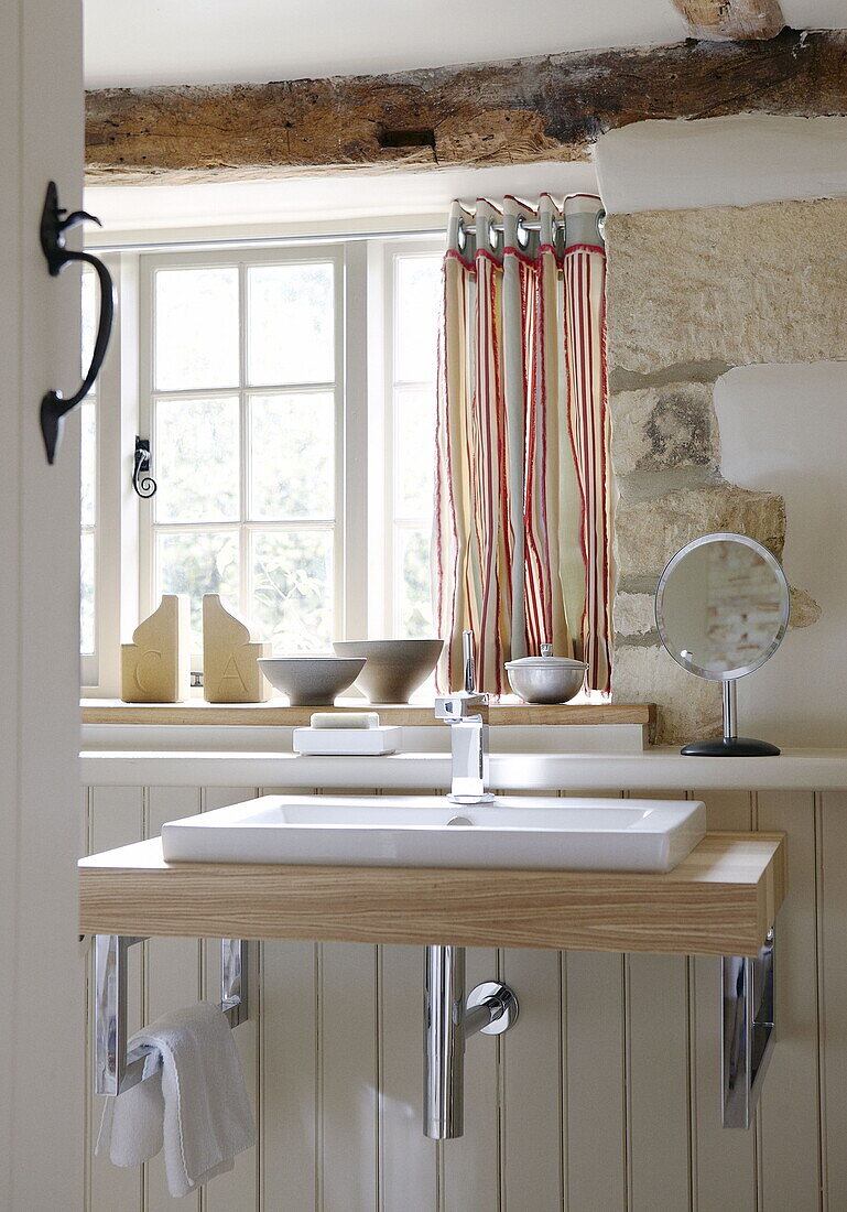 Wash basin and shaving mirror at window of renovated Cotswolds mill house England UK
