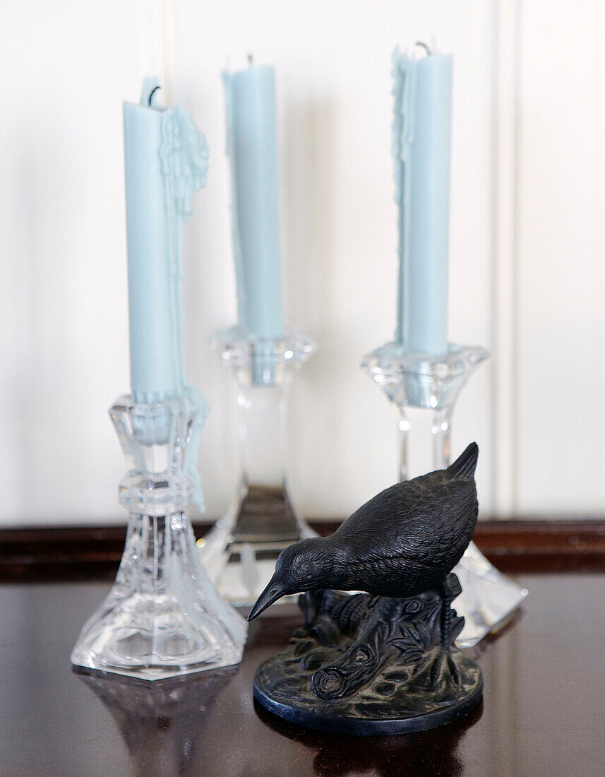 Bird statue and light blue candles in glass candlesticks Hampshire home England UK
