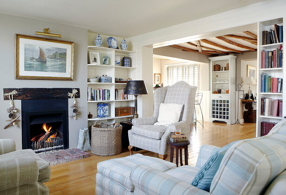 Wingbacked armchair at open fire with bookcases in Hampshire home England UK