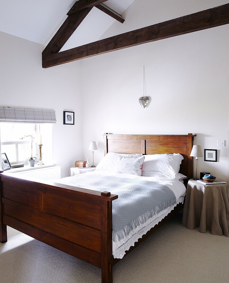 Wooden bed under beamed ceiling in Durham family home England UK