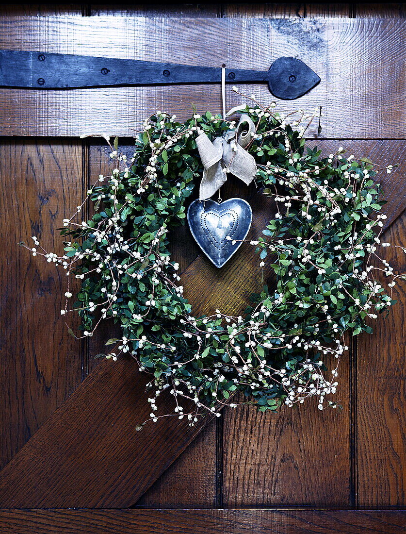 Heart in mistletoe wreath on wooden front door Forest Row Surrey England UK