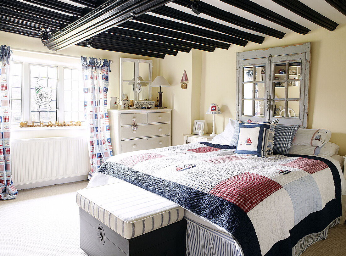 Patchworkdecke auf dem Bett in einem Zimmer mit Balkendecke Forest Row Bauernhaus Surrey England UK