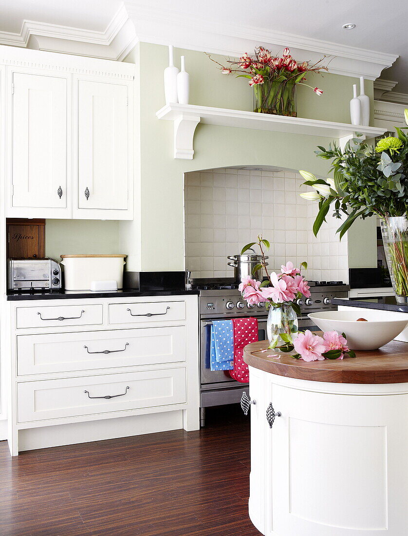 Einbaubackofen und weiße Einbauschränke mit Schnittblumen in einer Küche in Harrogate Yorkshire England UK