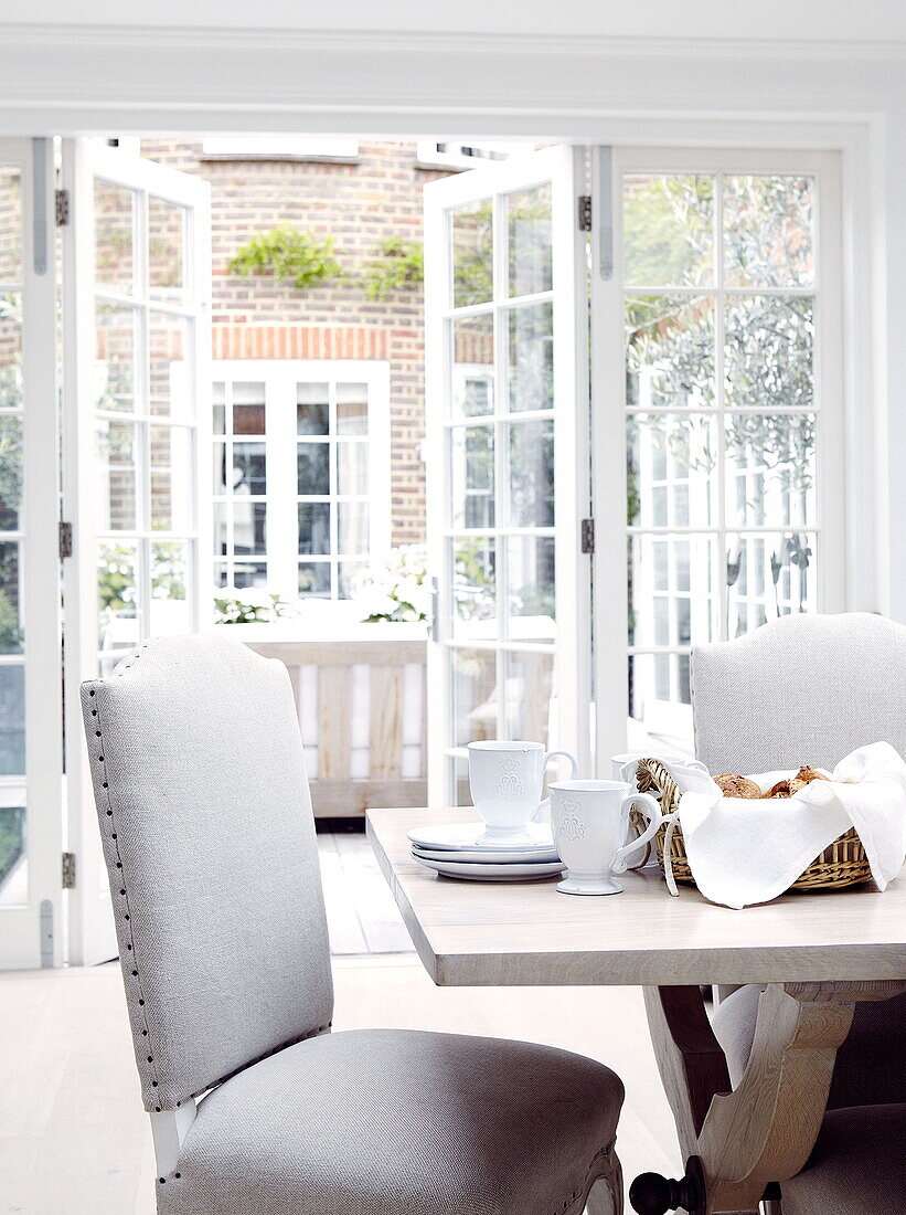 Frühstückstisch mit Blick durch Flügeltüren auf den Garten im Innenhof eines Londoner Hauses UK