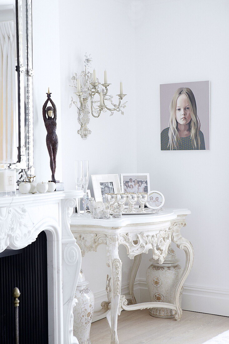 Family photographs on antique white side table in London home UK