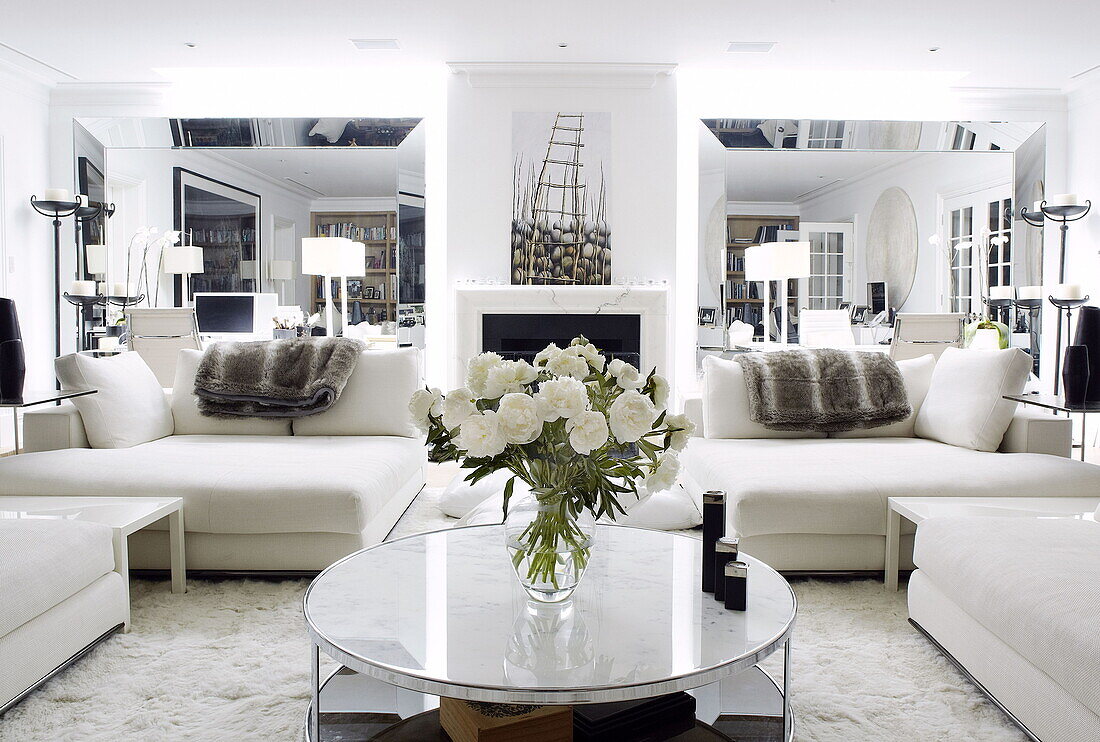 White sofas and circular coffee table in mirrored living room of London home UK