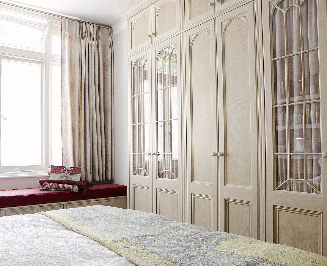 Kleiderschrank mit Glasfront und Fensterbank im Schlafzimmer eines Londoner Hauses UK