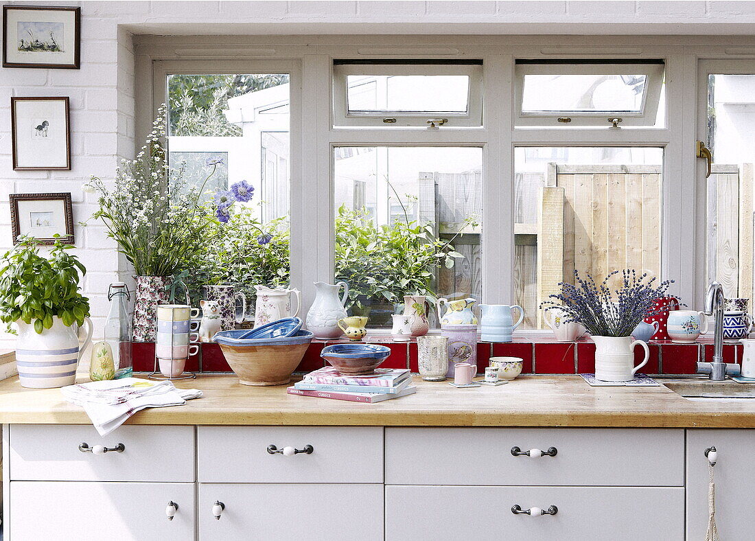Schnittblumen und Geschirr auf der Fensterbank eines Hauses in London UK