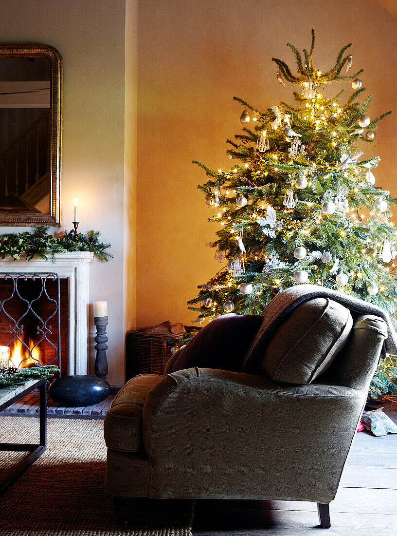 Sessel und Weihnachtsbaum vor dem Kamin in einem festlichen Haus in Oxfordshire, England, UK