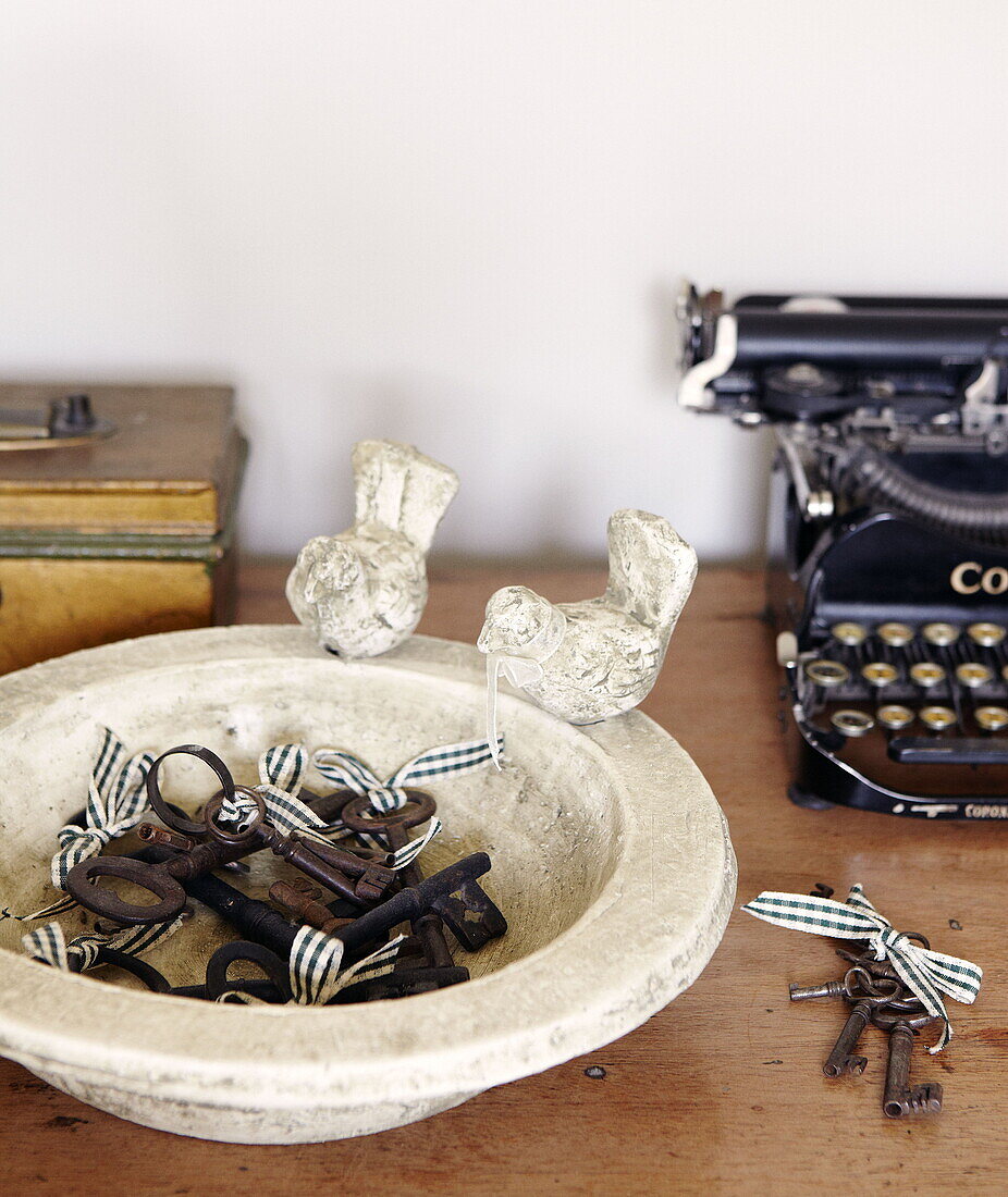 Antique typewriter and old keys in a bowl with figurine birds Gateshead Tyne and Wear England UK
