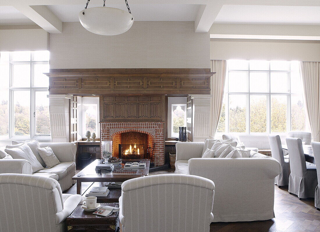 Lit fire with white sofas in seating area of country house Tunbridge Wells Kent England UK