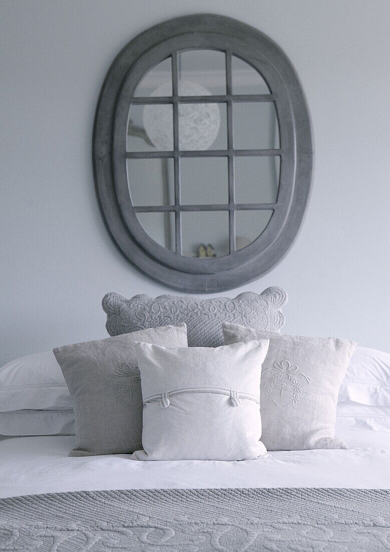 Verspiegelter Fensterrahmen über bestickten Kissen auf dem Bett im Landhaus Tunbridge Wells Kent England UK