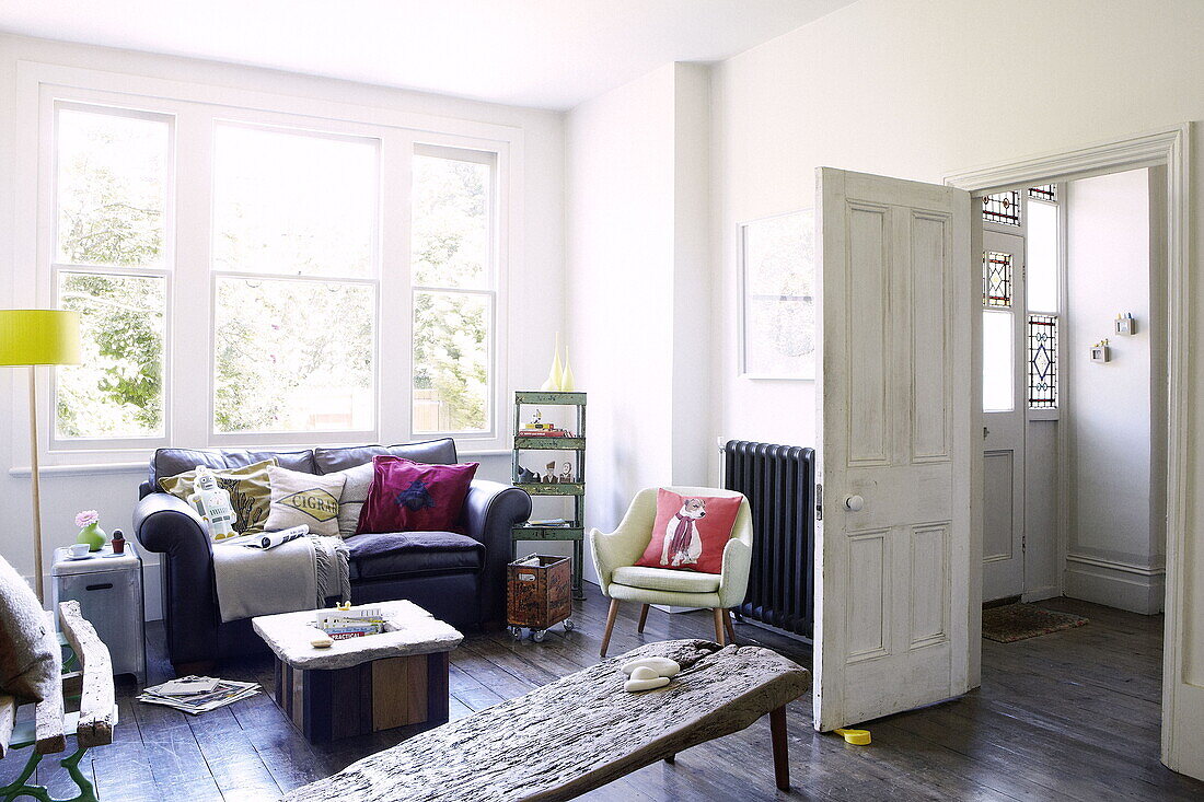 Sofa unter einem Fenster ohne Vorhang mit einem Tisch aus Treibholz in einem Londoner Einfamilienhaus UK