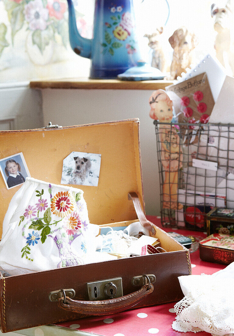 Bestickter Stoff und Fotos in einem alten Koffer in einem Haus in Oxfordshire, England, UK