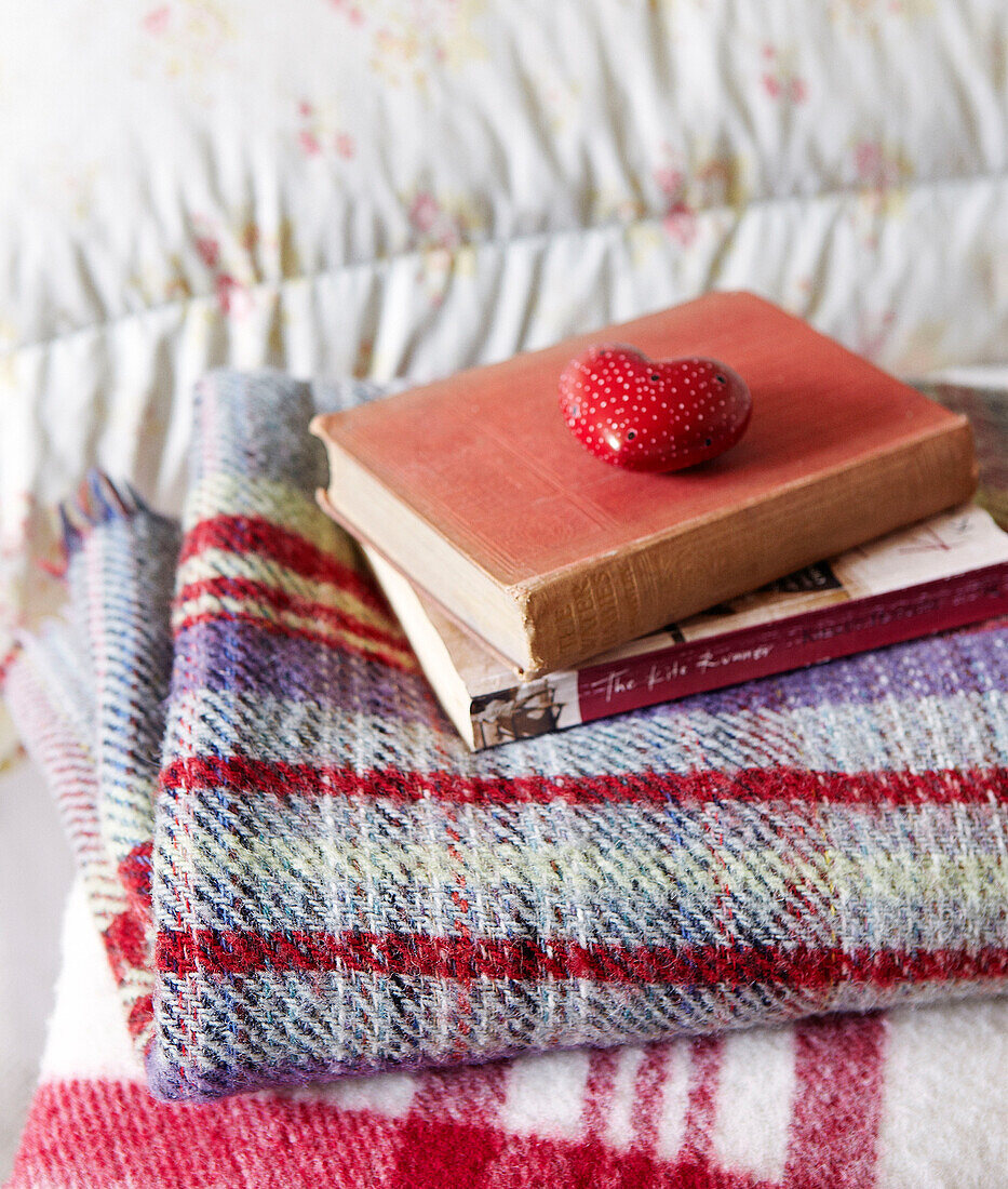 Scented pot pourri holder with books on tartan blanket in Oxfordshire bedroom, England, UK