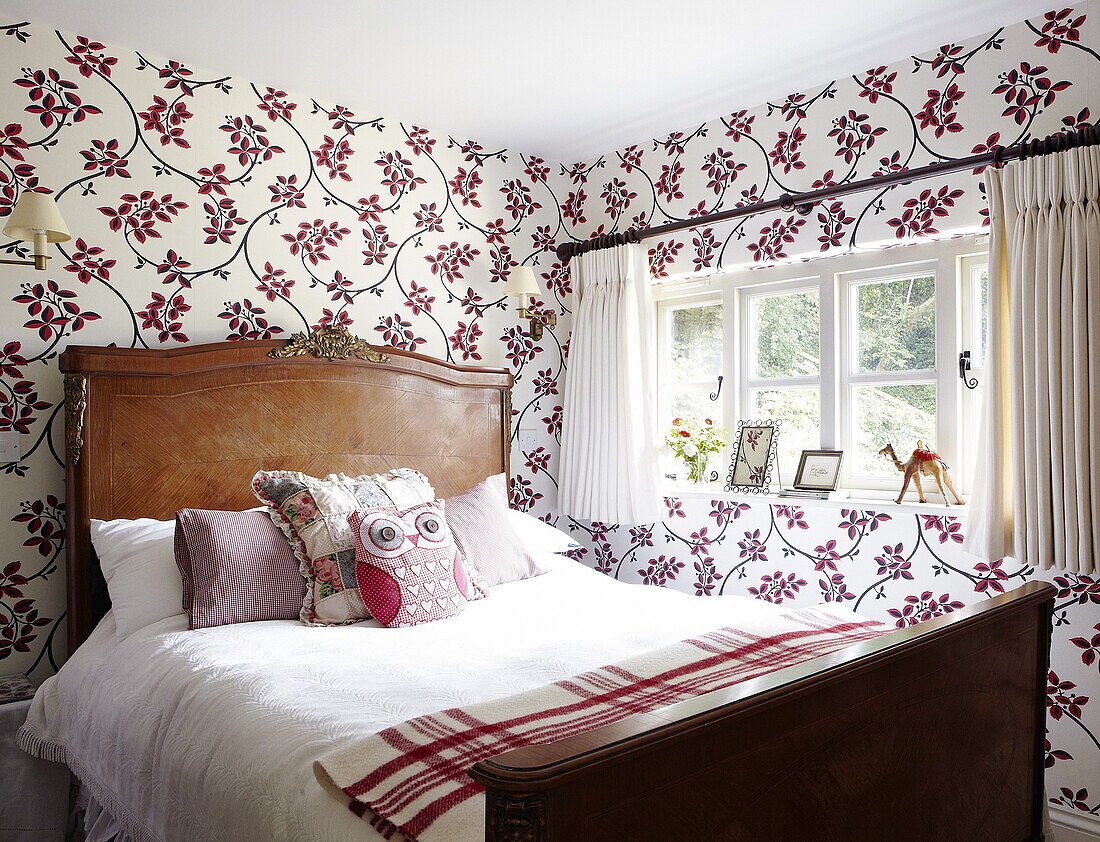 Antique wooden bed in contemporary papered room in Oxfordshire home, England, UK