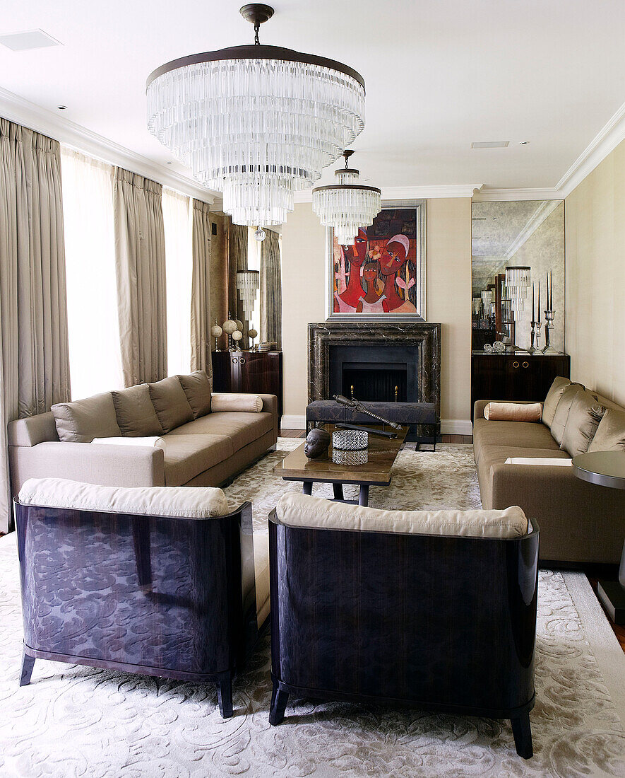 Matching armchairs and sofas below modern glass chandeliers in classic London home, England, UK