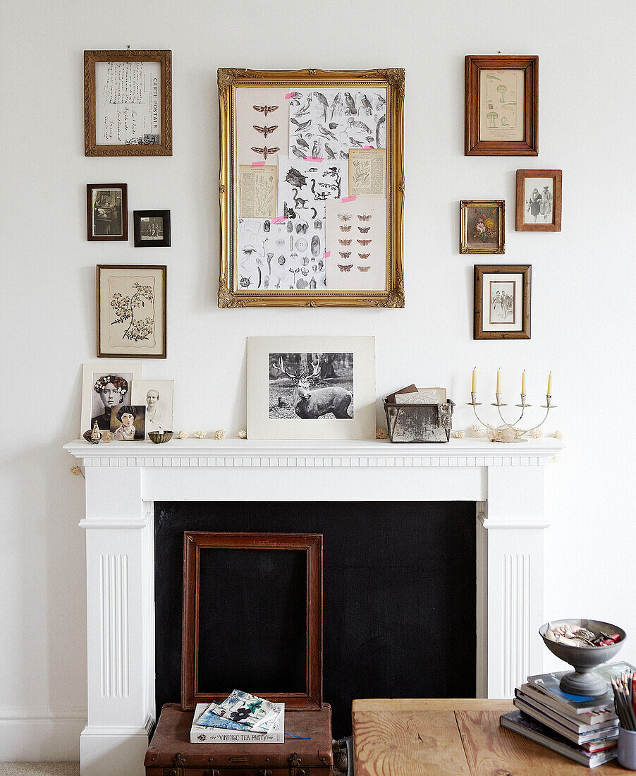 Collection of framed artwork above fireplace in living room in Hastings home, East Sussex, UK