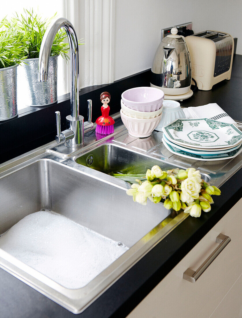 Plates and bowls with cut flowers in kitchen sink