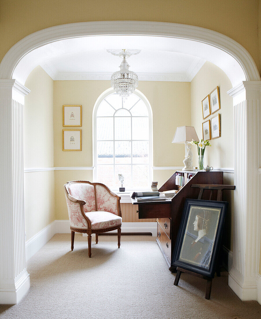 Armchair at wooden writing desk in recessed study at arched window in Warwickshire home, England, UK