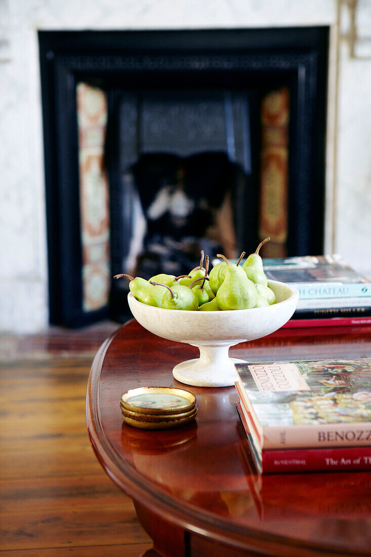 Schale mit Birnen und Büchern auf einem Couchtisch aus poliertem Holz in einem Haus in Warwickshire, England, UK