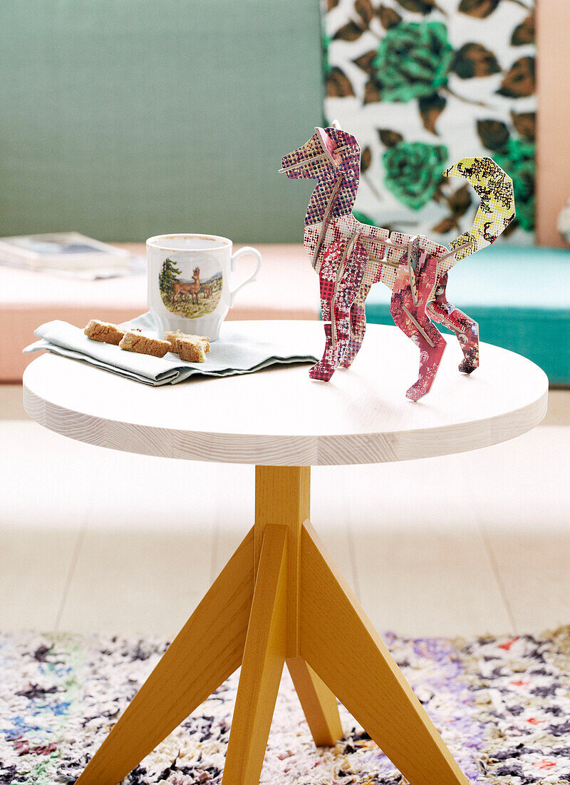 Modellhund auf rundem Holztisch mit Tasse und Keksen, Amsterdam, Niederlande