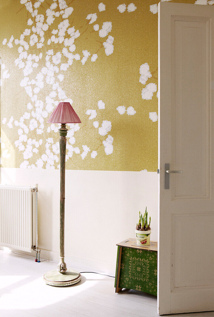 Standard lamp behind door of living room with blossom patterned wallpaper, Amsterdam, Netherlands