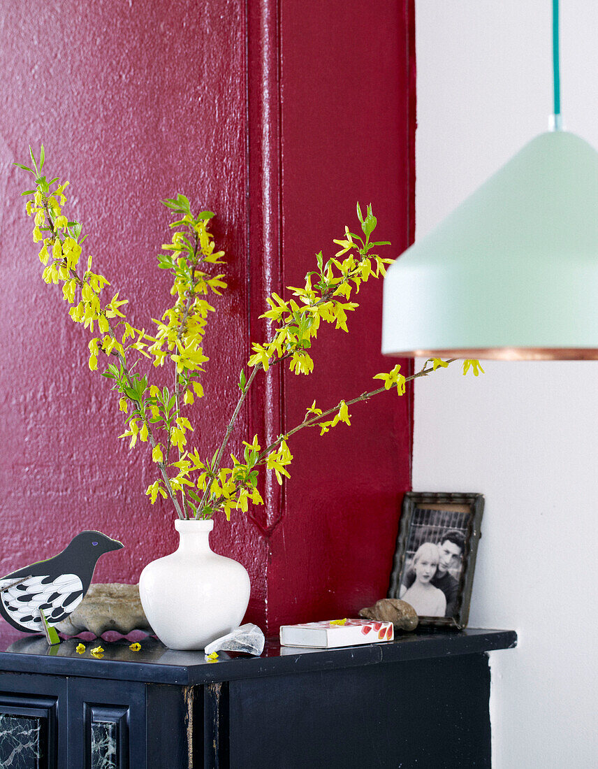 Yellow blossom in vase on mantlepiece with light green pendant light in contemporary apartment, Amsterdam, Netherlands