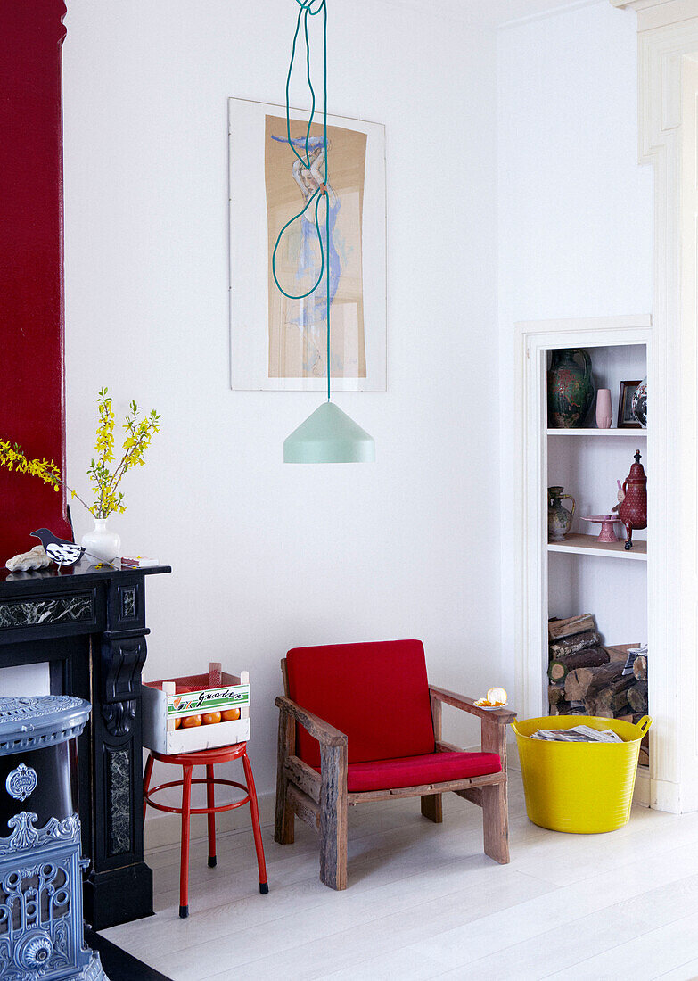 Red wooden armchair between shelving and fireplace in contemporary apartment, Amsterdam, Netherlands