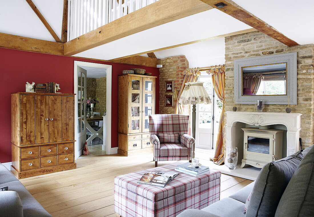 Holzschränke und Karo-Polstermöbel in einem Wohnzimmer mit doppelter Höhe, Oxfordshire, England, UK