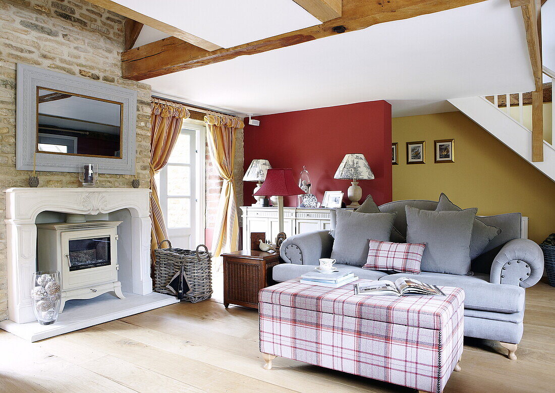 Light blue two-seater sofa at stone fireplace with woodburning stove in Oxfordshire, England, UK