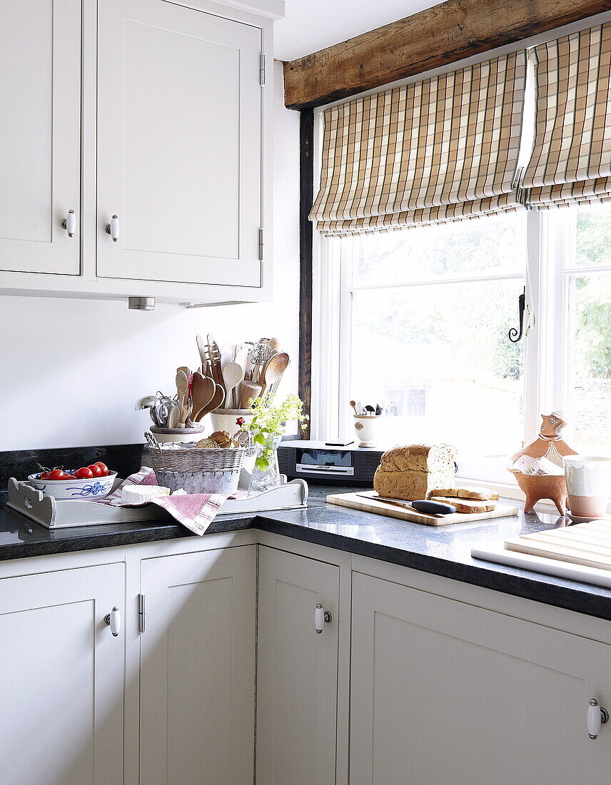 Holzlöffel und Brot auf Küchentisch am Fenster in Einbauküche, Oxfordshire, England, UK