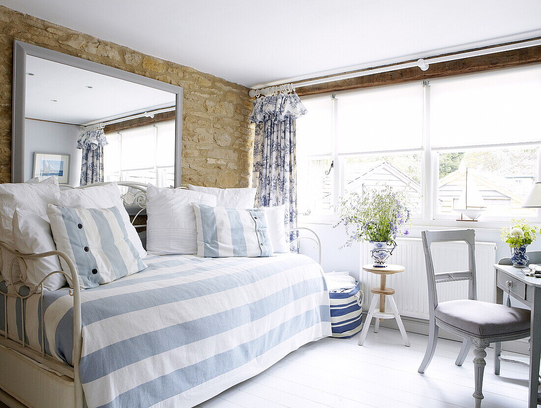 Striped light blue cover on day bed with large mirror in barn conversion, Oxfordshire, England, UK