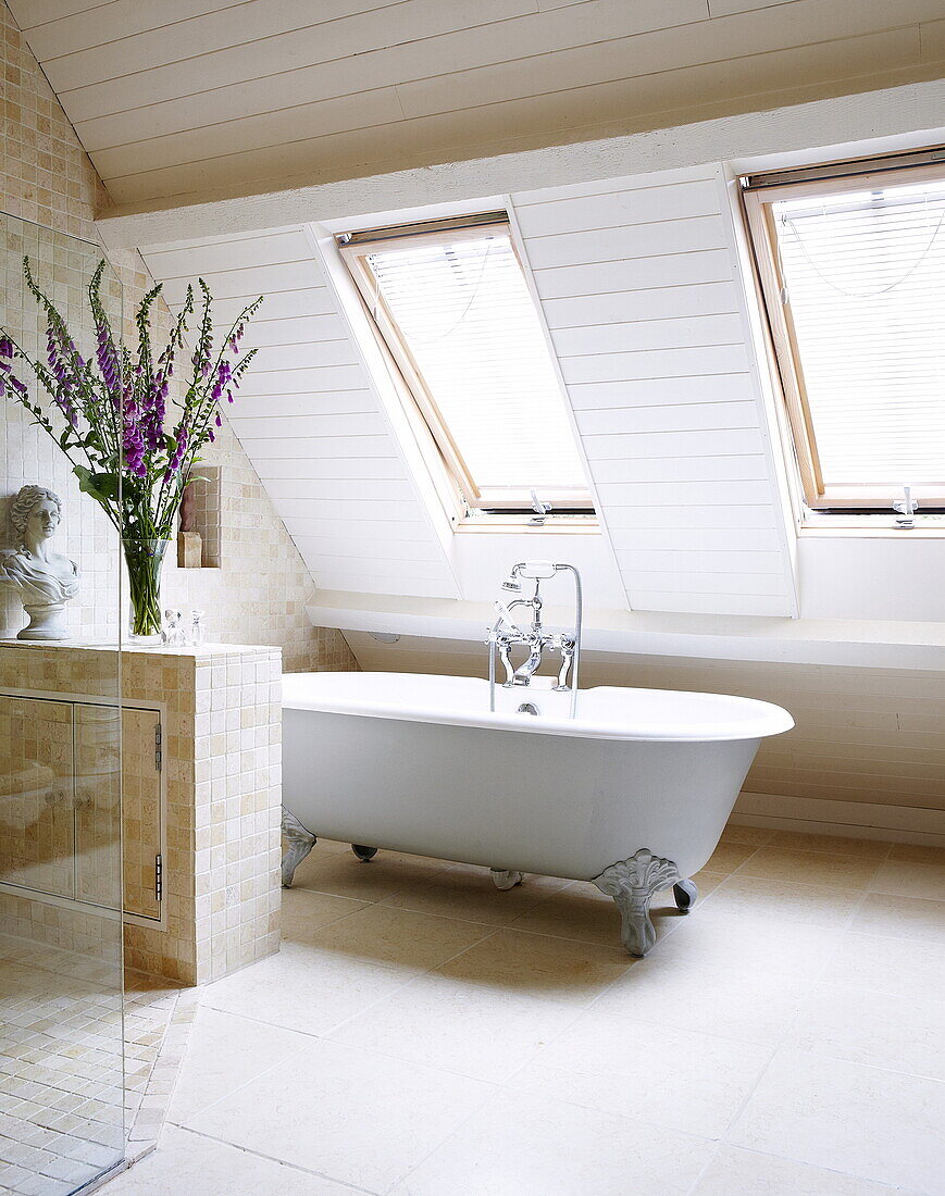 Freestanding rolltop bath below windows of attic conversion, Oxfordshire, England, UK