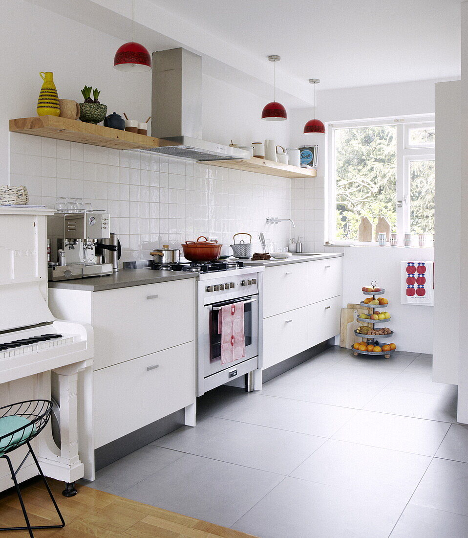 White fitted unit with piano and stainless steel oven and extractor in Bussum home, Netherlands