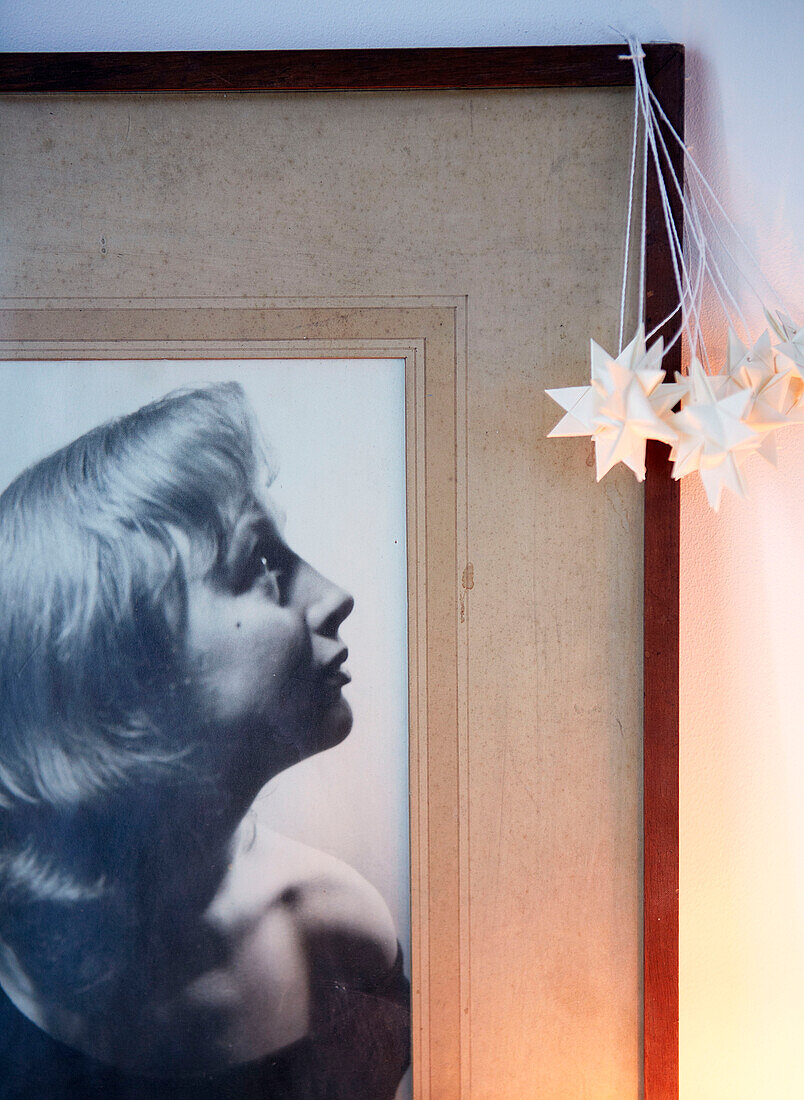 Dekorative Sterne hängen an einem Bilderrahmen mit einem Schwarz-Weiß-Fotoporträt in einem Haus in London, England, UK