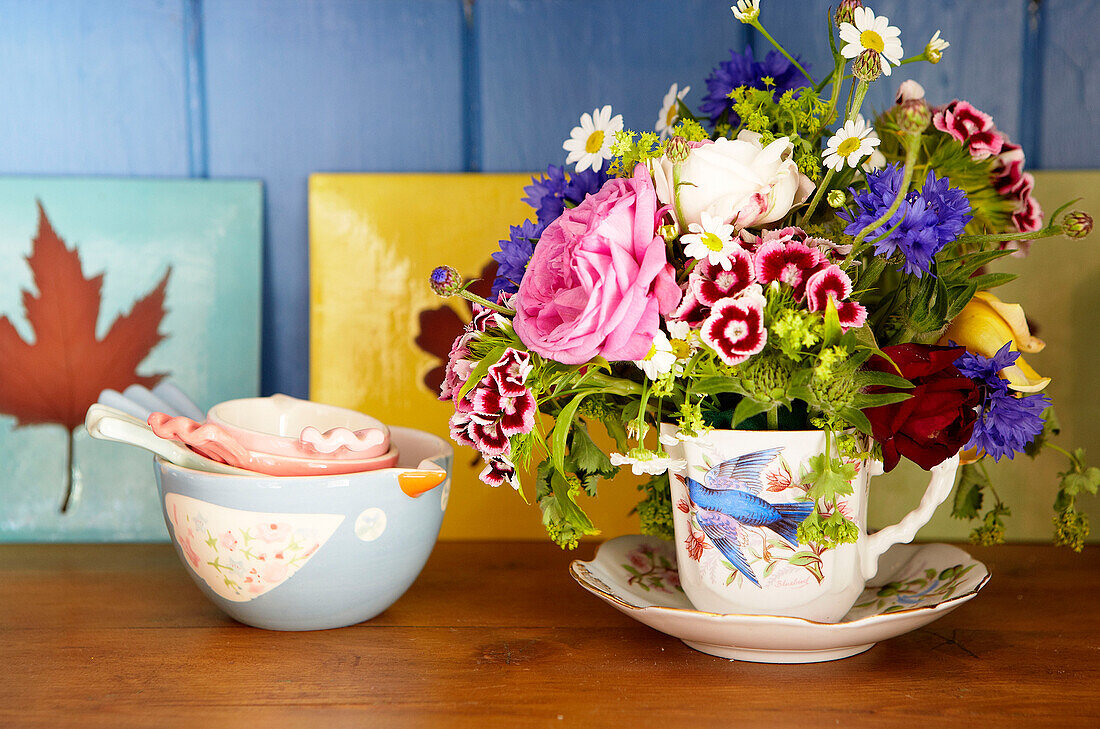 Cut flowers in teacup with bowl and tiles in Surrey farmhouse England UK
