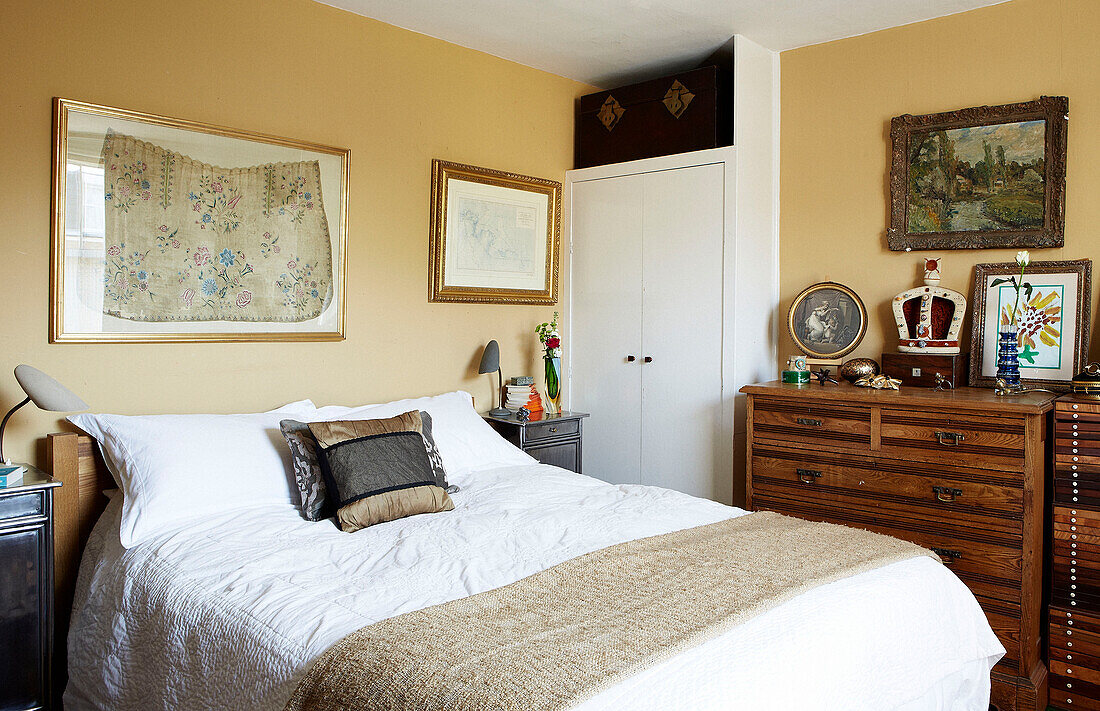 Vergoldete gerahmte Stickerei über dem Doppelbett mit Holzschubladen in einem Londoner Stadthaus England UK