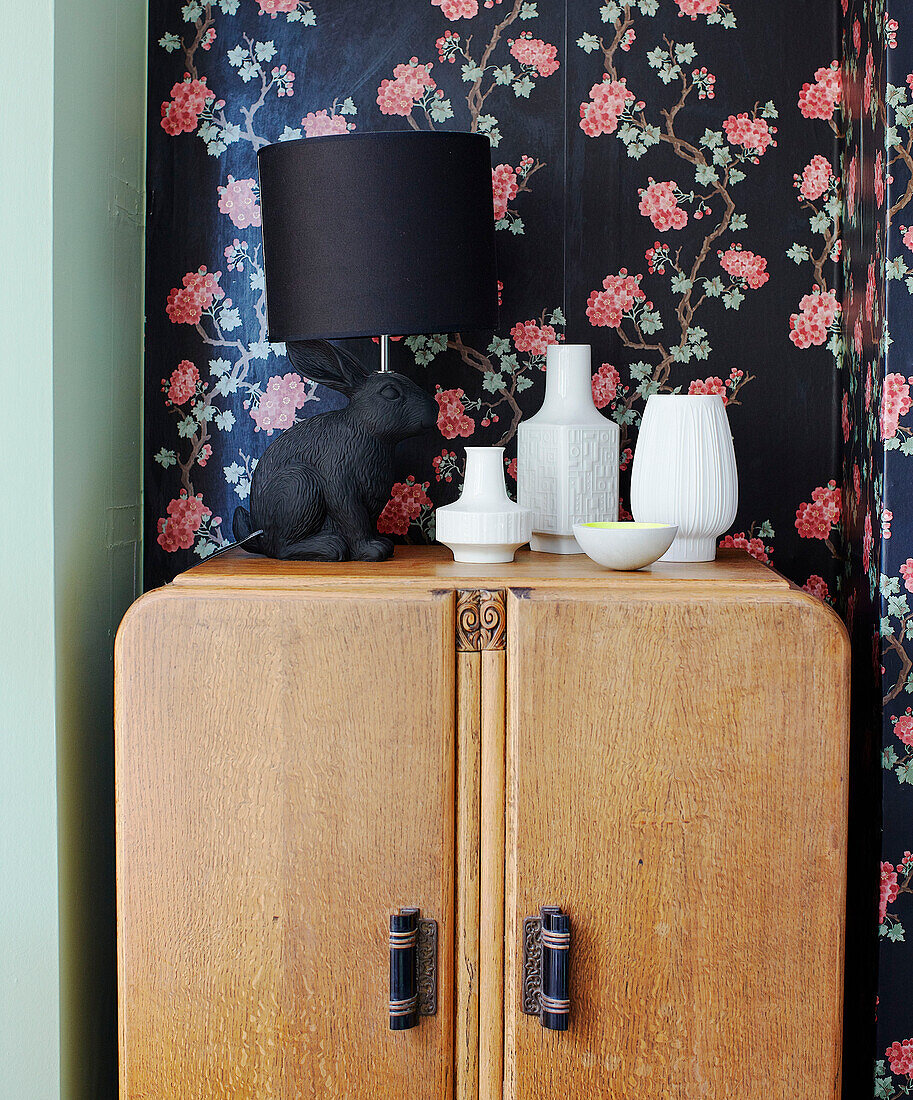 Ceramic vases and lamp on wooden wardrobe with floral wallpaper in family home Margate Kent England UK