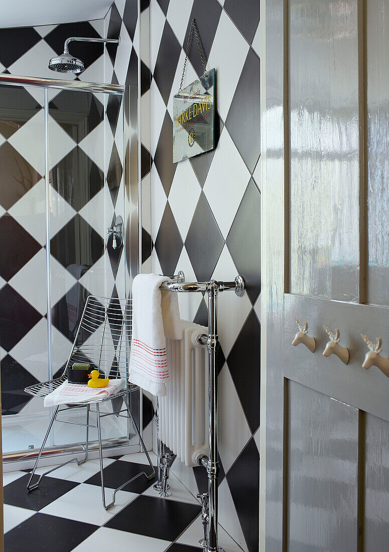 Türhaken und Heizkörper mit Duschkabine im karierten Badezimmer eines Einfamilienhauses in Margate, Kent, England UK