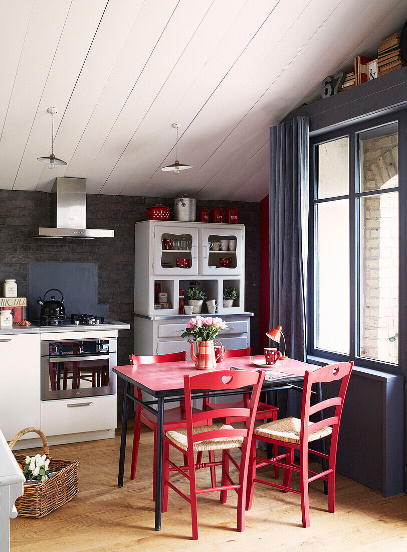 Roter Küchentisch und Stühle in der Küche eines umgebauten Schulhauses in der Bretagne, Frankreich