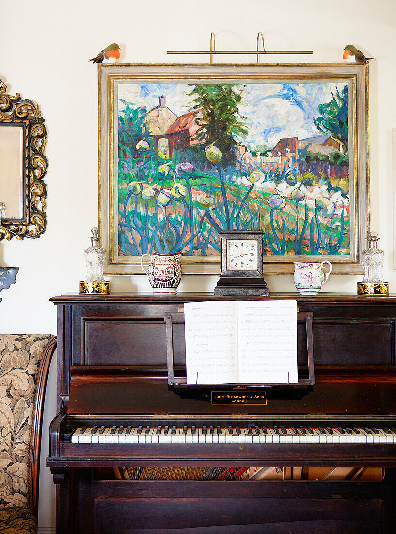 Framed artwork above piano with sheet music in Oxfordshire country house England UK