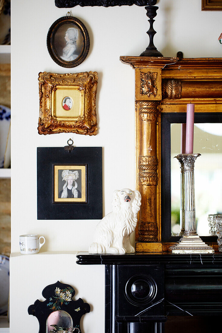 Vergoldetes gerahmtes Kunstwerk und Spiegel mit schwarzem Kaminsims in einem Landhaus in Oxfordshire England UK