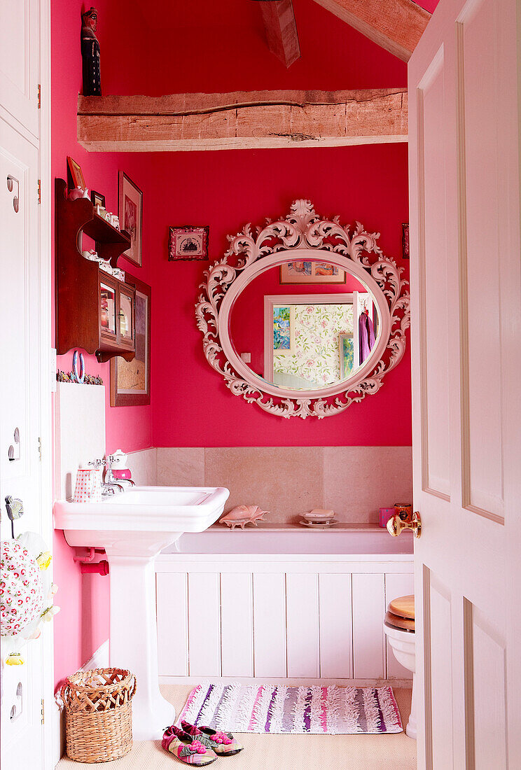 Verschnörkelter runder Spiegel über dem Bad in einem Landhaus in Oxfordshire, England, Vereinigtes Königreich