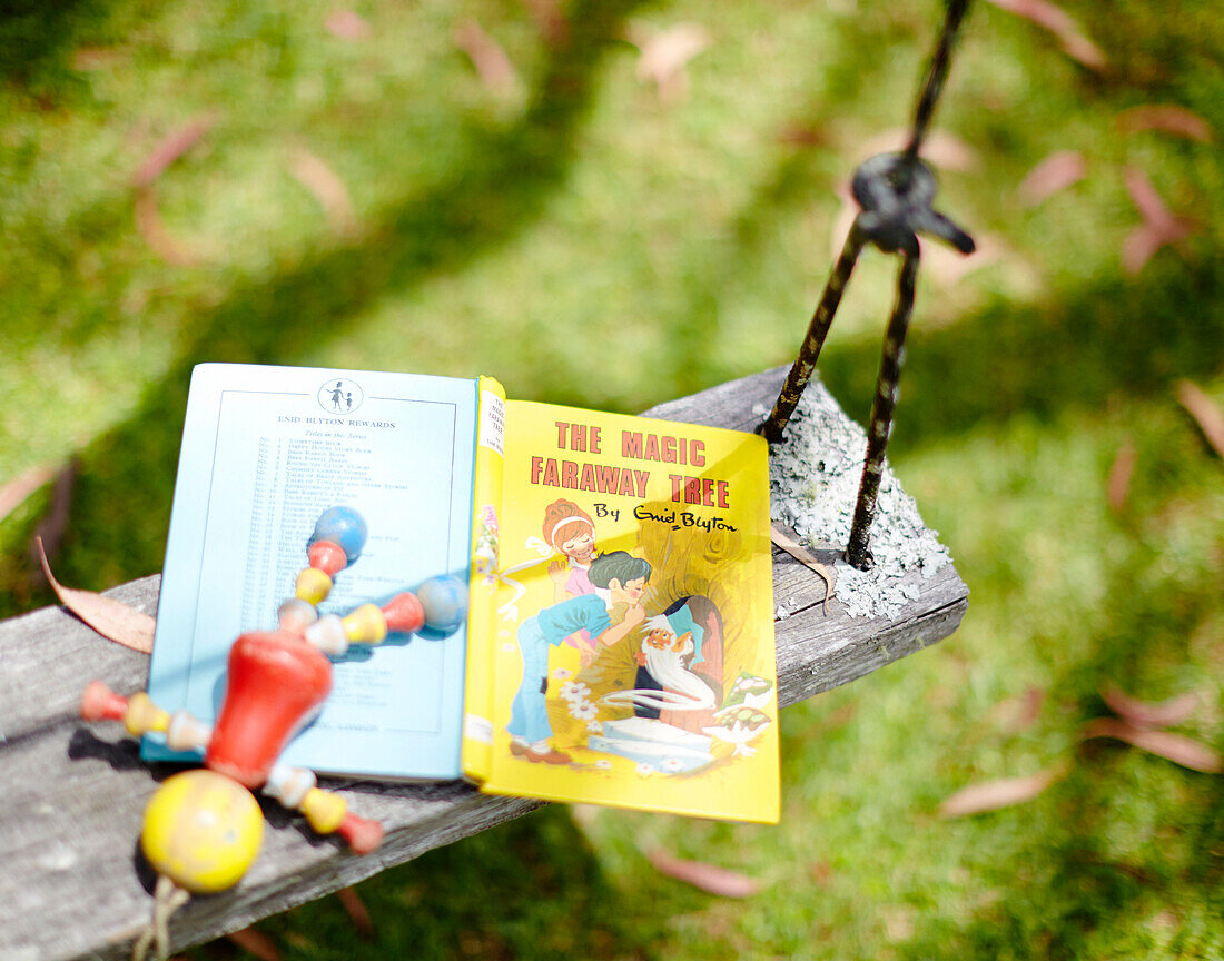 Märchenbuch und Spielzeug auf der Baumschaukel im Warkworth-Garten in Auckland auf der Nordinsel Neuseelands