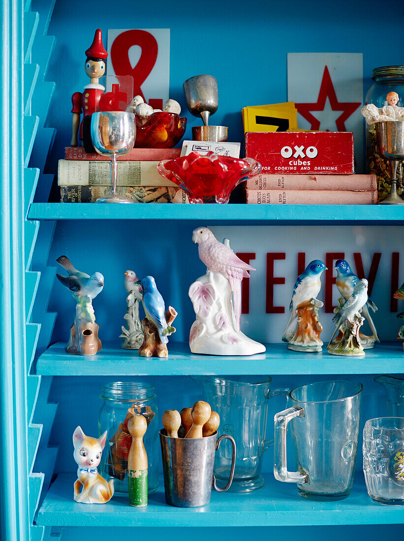 Parrot figurines with vintage toys on bright blue shelving in Auckland home North Island New Zealand