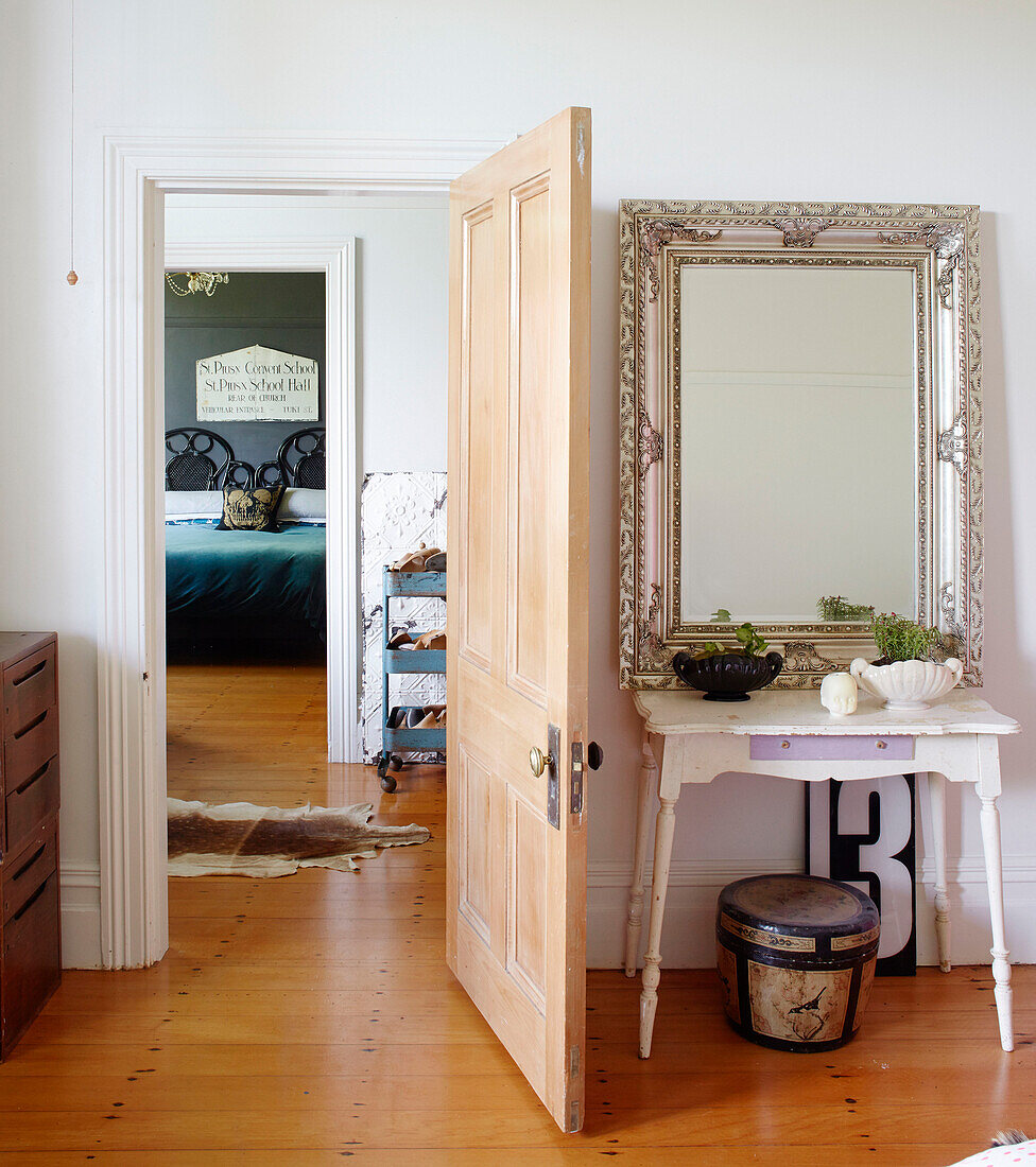 Large silver mirror on side table behind open door with view to bedroom in Auckland home North Island New Zealand