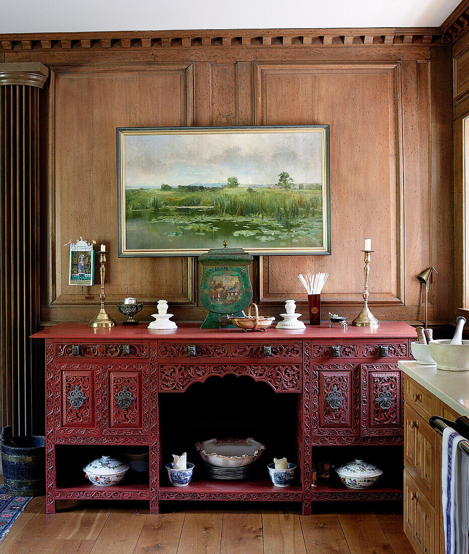 Framed artwork over carved wooden sideboard in traditional country house Welsh borders UK